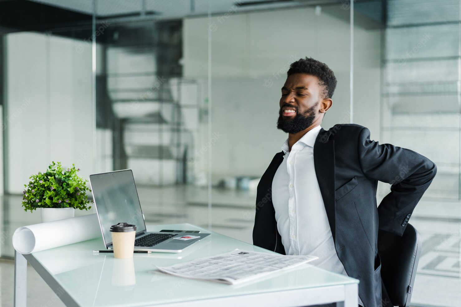 man at desk touching aching back